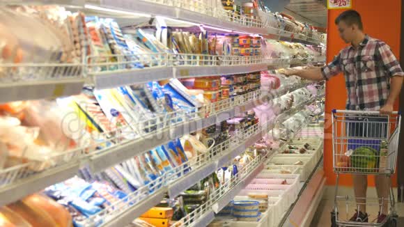 带着购物车的年轻人在冷藏区的超市冷藏食品杂货有人来了视频的预览图