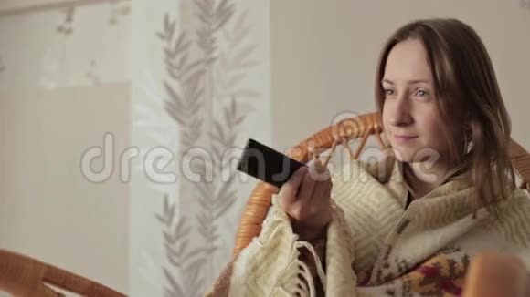 年轻女子裹着毯子拿着遥控器视频的预览图
