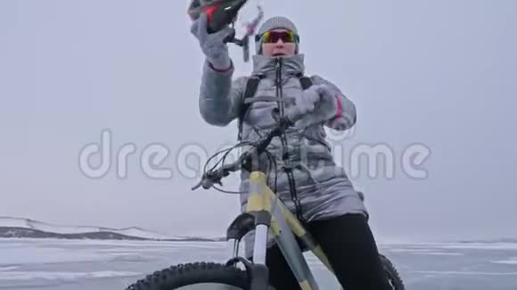 女人穿着运动装备女孩穿着银色羽绒服自行车背包和头盔冰的冰视频的预览图