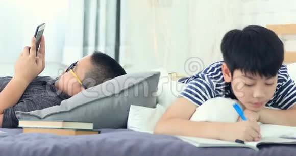 亚洲男孩在床上做作业和看书视频的预览图