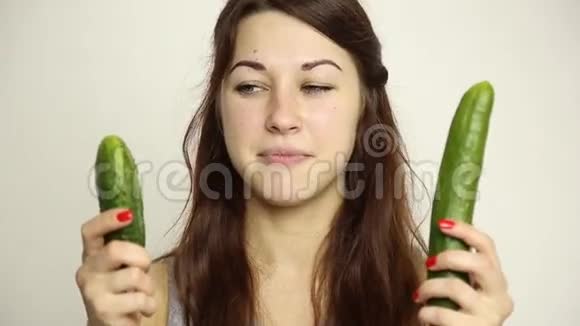 美丽的年轻女人吃蔬菜小黄瓜或大黄瓜的选择健康食品坚固的牙齿概念视频的预览图