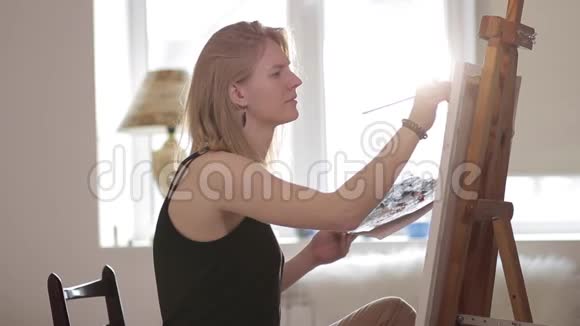 女画家坐在窗边画水彩画视频的预览图