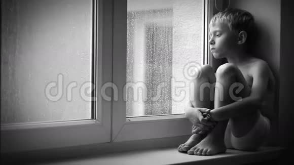 寂寞的小男孩透过窗户玻璃看雨滴视频的预览图