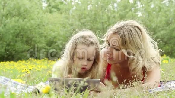 美丽的女人和女孩在平板电脑上玩耍在大自然中视频的预览图