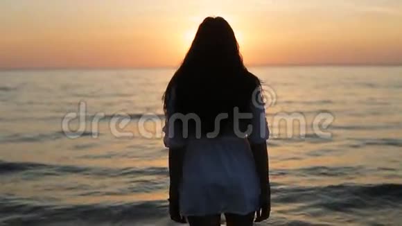 一个女孩在日落时缓慢地走进大海视频的预览图
