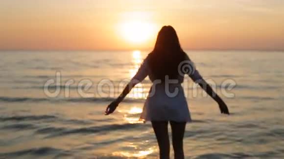 一个女孩在日落时缓慢地走进大海视频的预览图