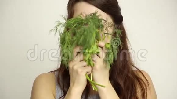 美丽的年轻女人吃蔬菜拿着迪尔和欧芹健康食物健康身体概念视频的预览图