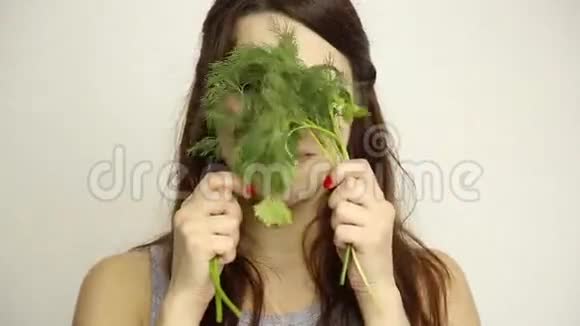 美丽的年轻女人吃蔬菜拿着迪尔和欧芹健康食物健康身体概念视频的预览图