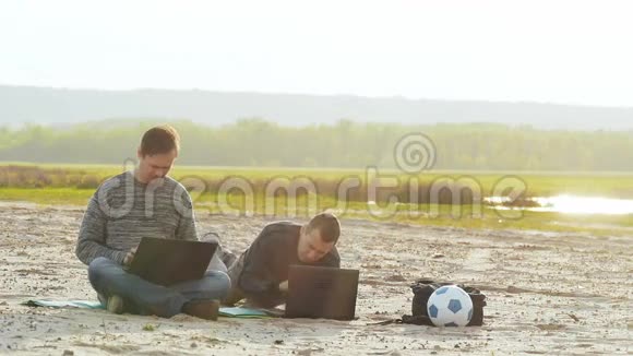 两个男人拿着笔记本电脑在沙滩慢动作视频上视频的预览图