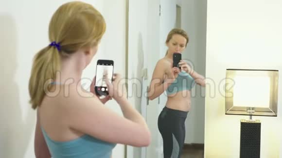 超重和减肥的概念一个女人看着镜子里的自己给她的身材拍照比较视频的预览图