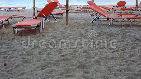 空的日光浴床矗立在碧海边的沙滩上视频的预览图