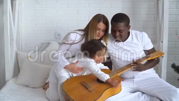 年轻幸福的多民族家庭母亲父亲和小女儿在圣诞节和圣诞节的背景下穿着白色衣服视频的预览图