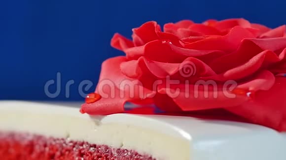 带有巧克力装饰的白色蛋糕和深蓝色背景的红色杏仁糖玫瑰装饰着可食用红玫瑰的蛋糕视频的预览图