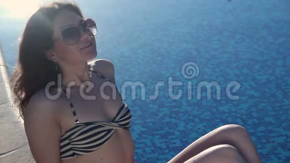 炎热的模特在阳光明媚的避暑胜地休息游泳池里有蓝色的水视频的预览图