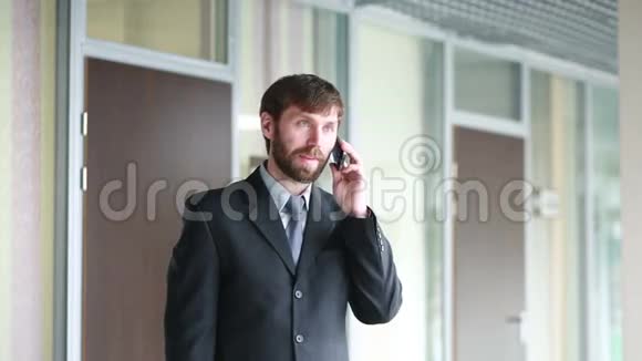 成功的商人在办公室内部站着时会用电话交谈视频的预览图