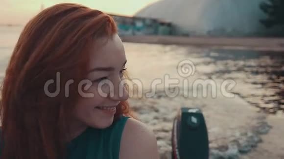 漂亮的红发女孩穿着绿松石的裙子在摩托艇上夏日之夜微笑视频的预览图