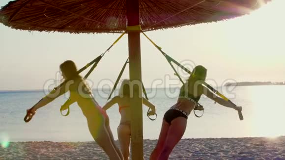 三名运动员穿泳衣的年轻女性教练用健身TRX系统做运动TRX悬架视频的预览图