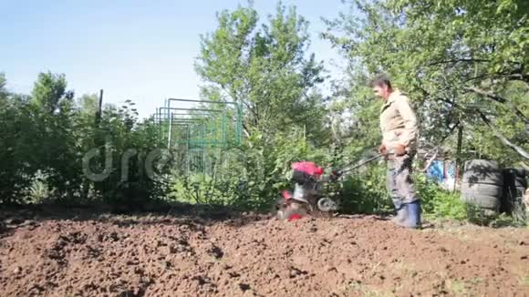 一个人是郊区的农民一个菜园用一个耕种者一个手动马达犁投掷粘土和视频的预览图