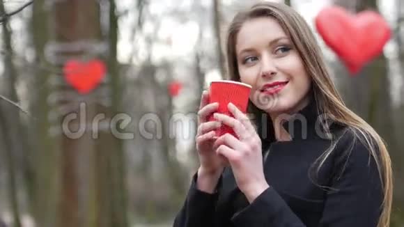 年轻漂亮的金发女郎在秋天公园的背景上摆着外卖咖啡视频的预览图