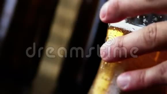 男人在啤酒瓶的背景前喝泡沫啤酒视频的预览图
