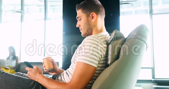男性高管在喝咖啡时使用手机视频的预览图