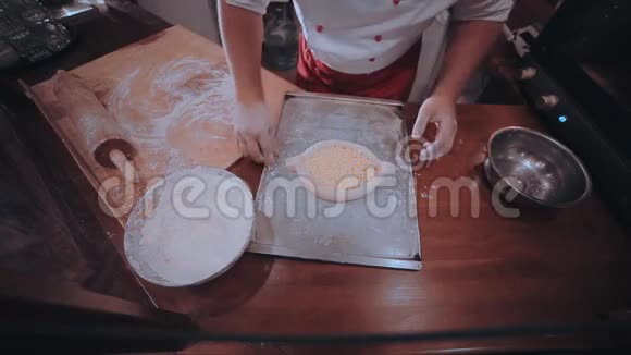 面包师把面团放在一张铺有面粉的木制餐桌上视频的预览图