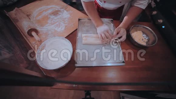 面包师把面团放在一张铺有面粉的木制餐桌上视频的预览图
