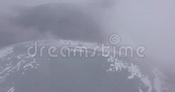 照相机在雾中飞过湖面和白雪覆盖的森林空中摄影4K视频的预览图