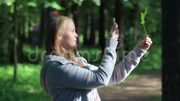 年轻的女人给叶子拍照视频的预览图