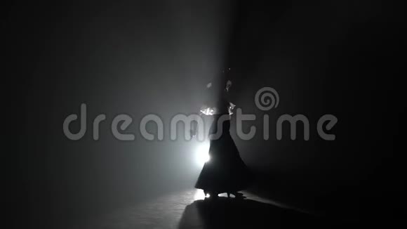 女人手里拿着蓖麻子跳舞从后面的光烟雾背景视频的预览图