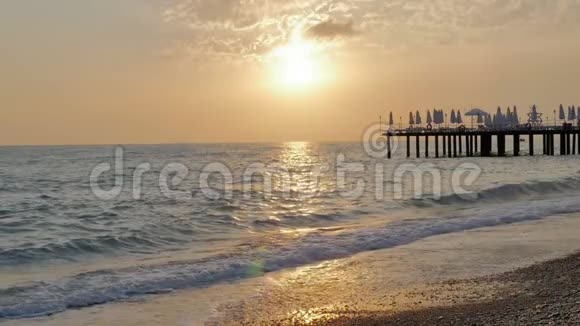 五彩缤纷的日落海浪和泡沫的海景码头和卵石海滩视频的预览图