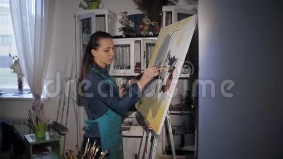 女孩艺术家在画架上画油视频的预览图