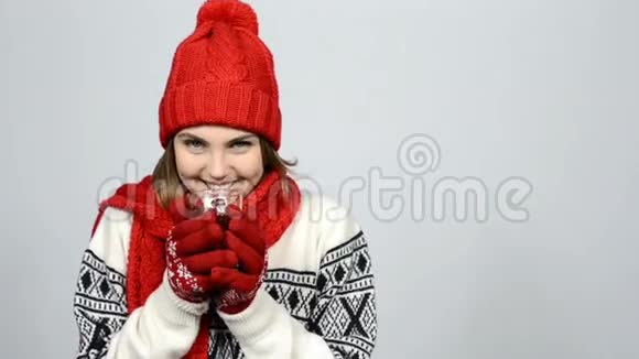 冬天的女孩戴着红色的温暖针织帽子和围巾手捧一杯茶视频的预览图