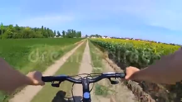 一个人骑着自行车在土路上穿过田野视频的预览图