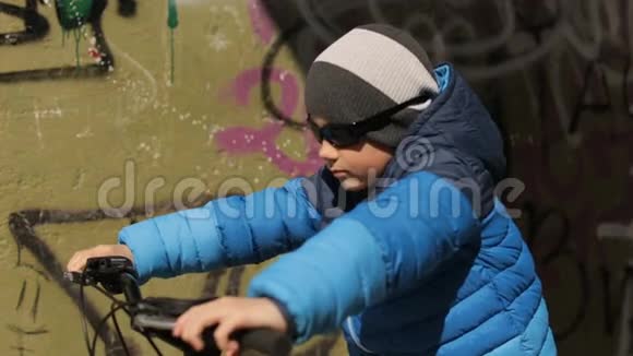 一个戴太阳镜的男孩坐在自行车上全高清视频视频的预览图