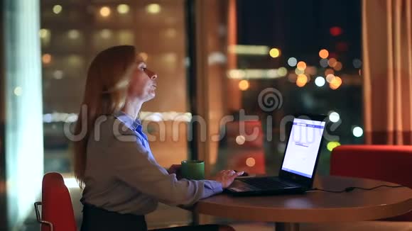 漂亮的金发商务女性在执行办公室加班城市灯光在背景中可见视频的预览图