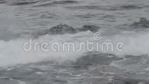 波浪在淹没的岩石上翻滚视频的预览图