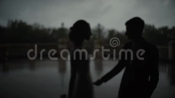 剪影一对幸福的夫妇抱在一起男人和女人站在拱门里手牵着手慢点视频的预览图