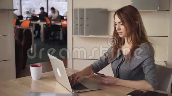 网上银行美丽的女人在工作场所用信用卡支付视频的预览图