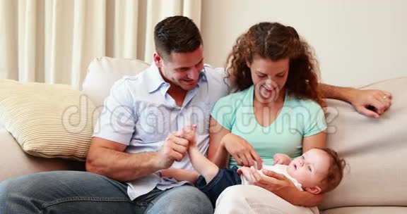 快乐的一对夫妇和他们的小儿子在沙发上视频的预览图