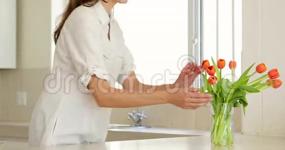 女人闻着她的郁金香花瓶对着镜头微笑视频的预览图