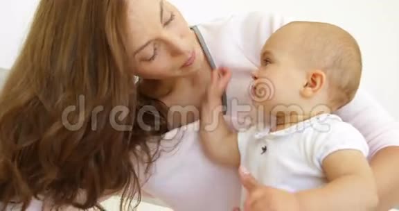 漂亮的年轻妈妈在床上和女婴玩耍视频的预览图