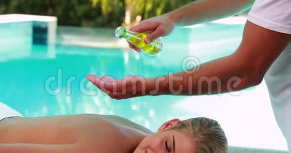 安静的金发美女在泳池边按摩视频的预览图