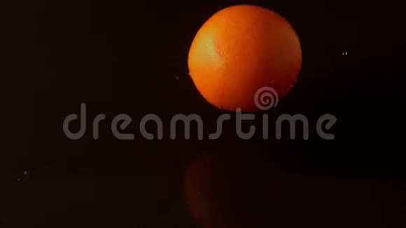 橙色滴落在潮湿的黑色表面视频的预览图
