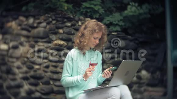 有笔记本电脑和文件的女人在石墙的背景上一杯酒和一杯酒视频的预览图