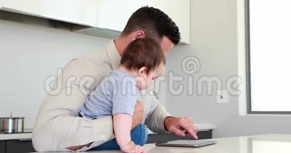 父亲在工作前抱着孩子用平板电脑视频的预览图