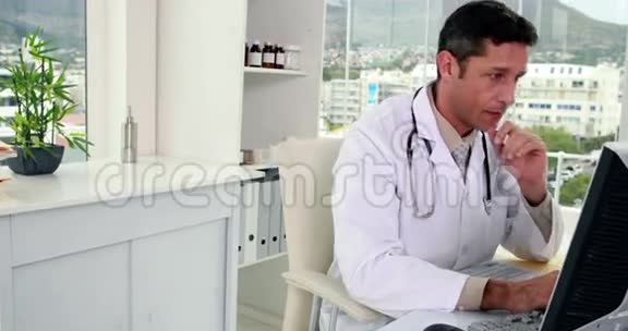 一位英俊的医生在办公桌前微笑着看着摄像机视频的预览图