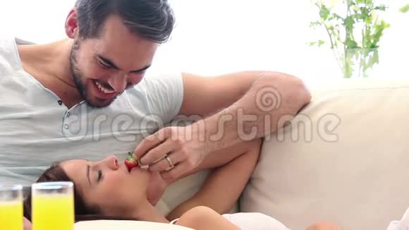 可爱的一对夫妇在沙发上吃草莓视频的预览图