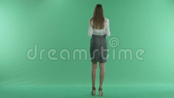 女商人在绿色背景下拿着蓝色屏幕视频的预览图