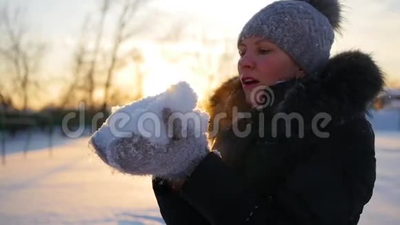 女孩用双手吹雪日落背景视频的预览图